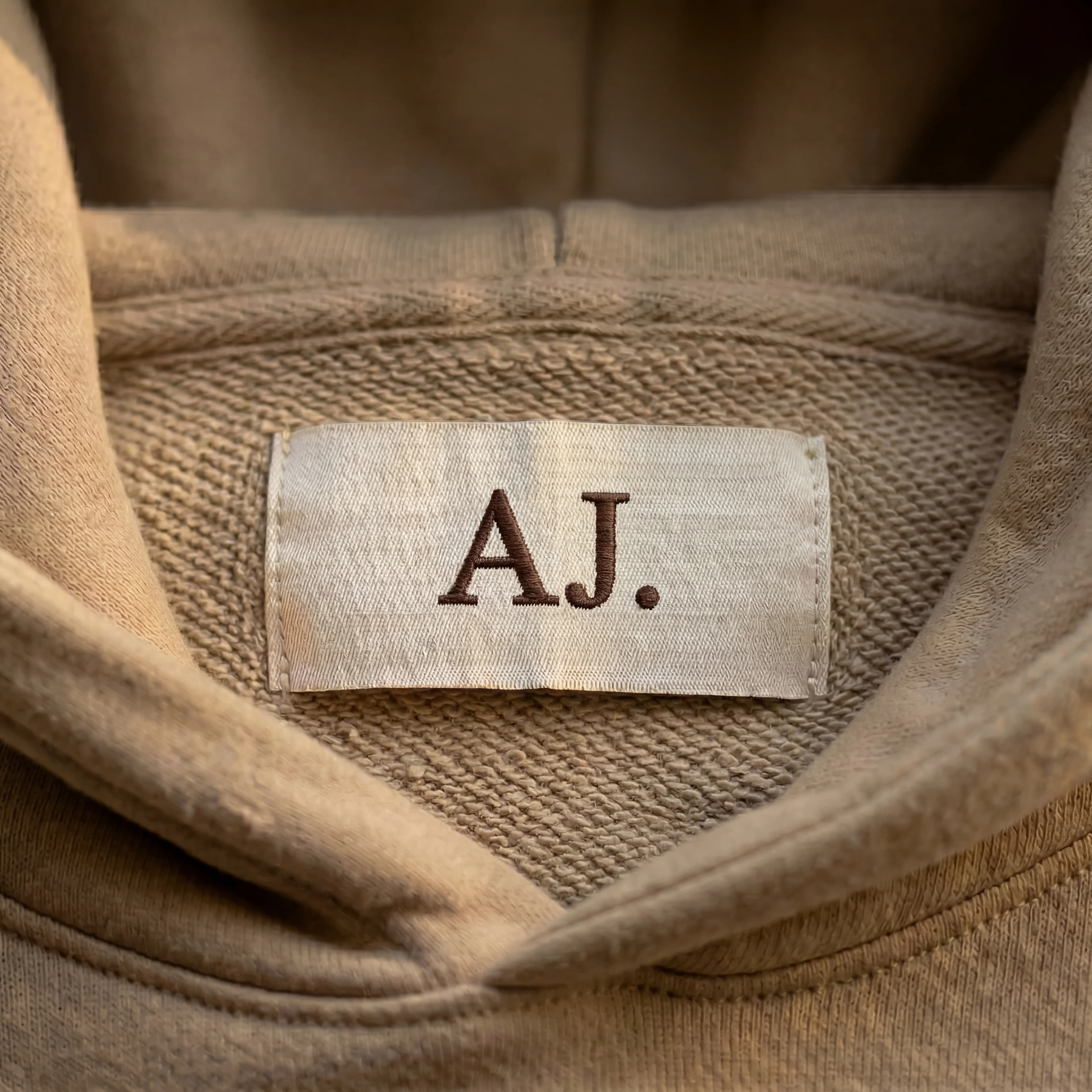 Taupe hoodie interior showing embroidered monogram: E.M.